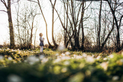 The small girl stands near trees